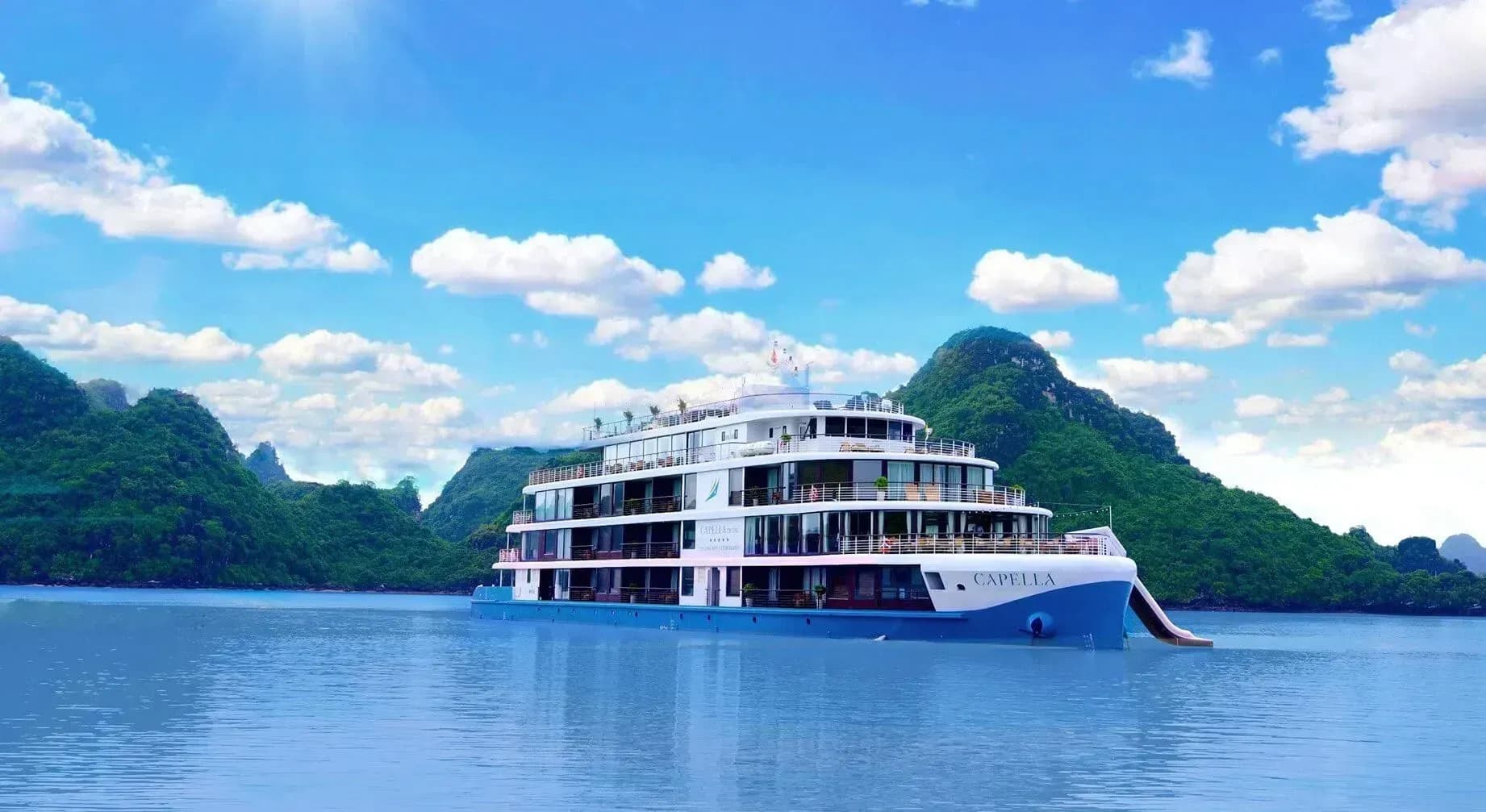 Capella cruise on the sea with green mountains and blue sky.