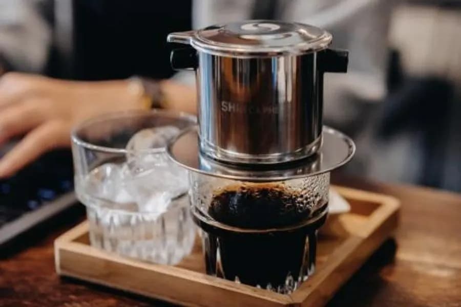 Vietnamese drip coffee with ice glass on wooden table.  