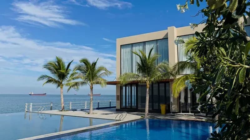 Image of a luxury beachfront resort featuring an infinity pool and lush palm trees at Marina Bay Vung Tau Resort & Spa.