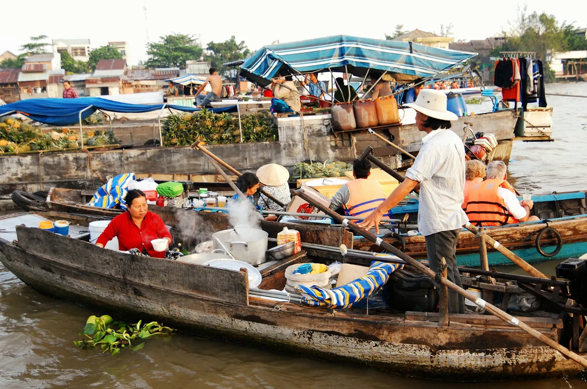 Early morning at Cai Rang Floating Market, bustling with tourists and vibrant scenes of trade, featuring an array of fresh fruits, bread, and livestock on boats 3