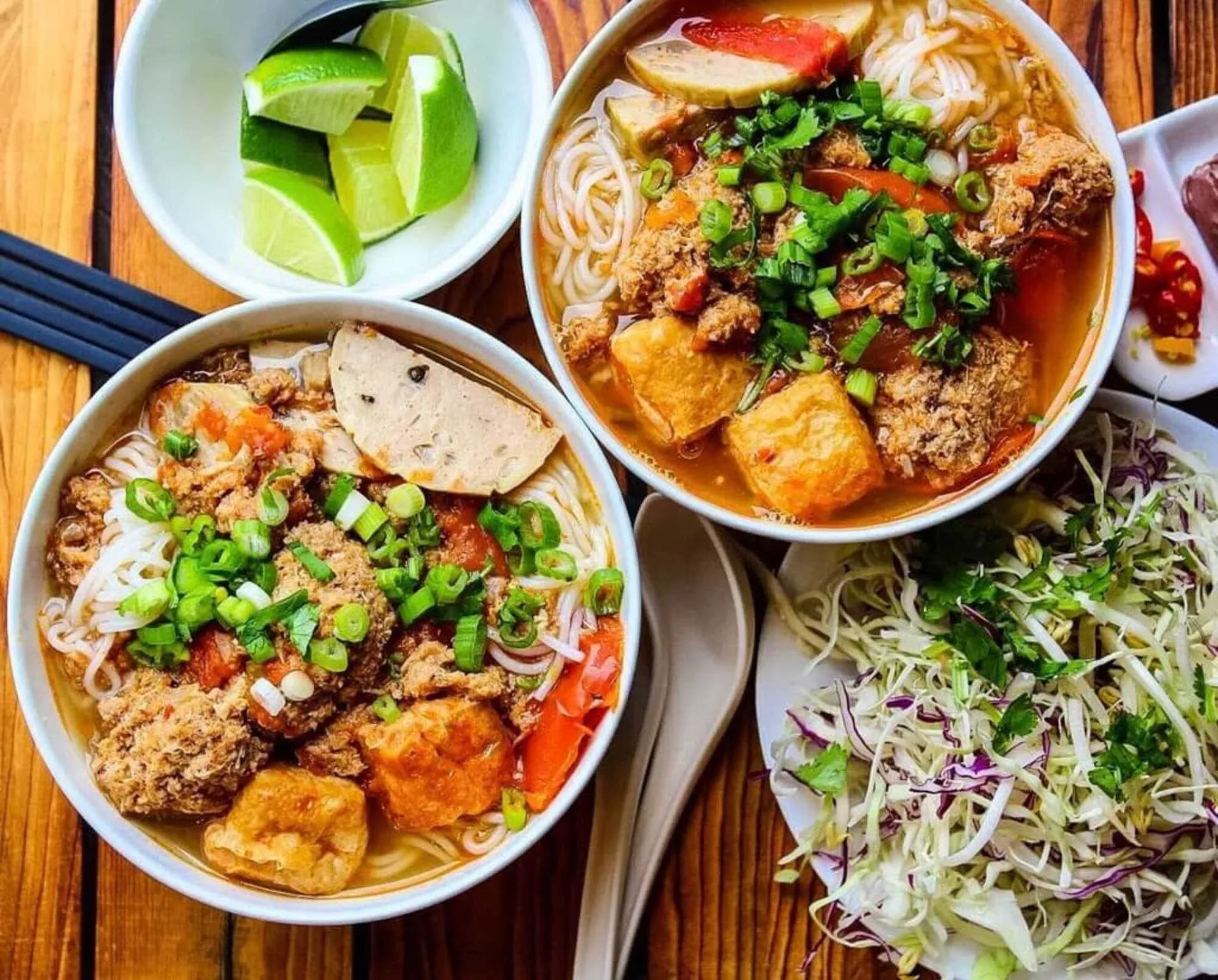 Bun Rieu Cua – a famous Vietnamese noodle dish, with broth made from fresh ground field crab, tomatoes, fried tofu, and shrimp paste, served with fresh rice noodles, raw vegetables, and a little spicy chili.