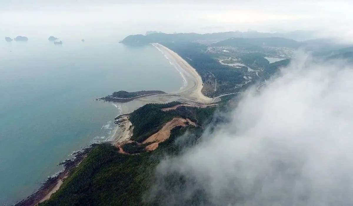 Clear blue sea, with long golden sand beach of Ngoc Vung Island seen from above