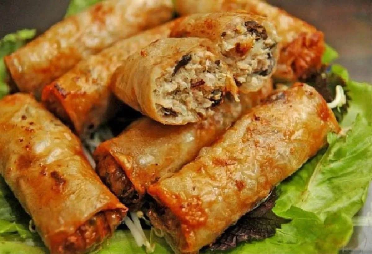 Hanoi fried spring rolls – a traditional dish with crispy skin, minced meat, shiitake mushrooms, and vermicelli, tightly rolled and fried, served with sweet and sour fish sauce and fresh herbs