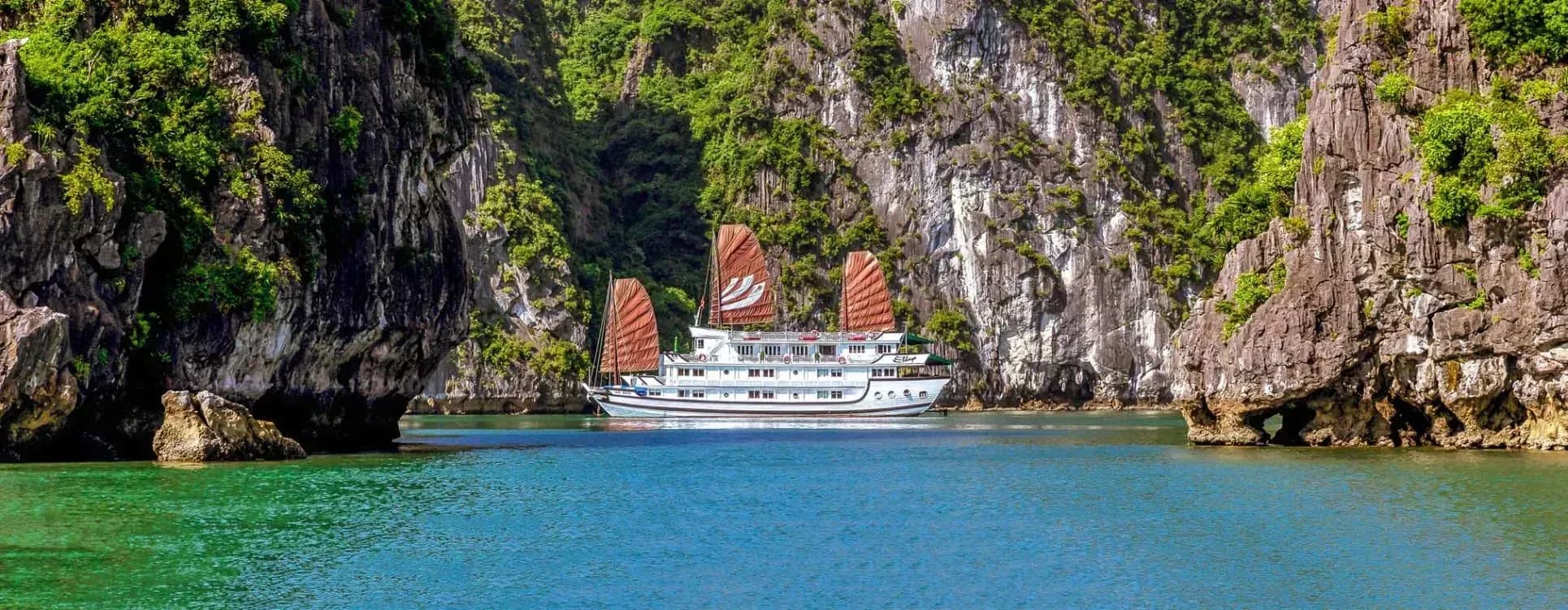 Bhaya Cruise is moving between mossy limestone cliffs in Ha Long Bay.