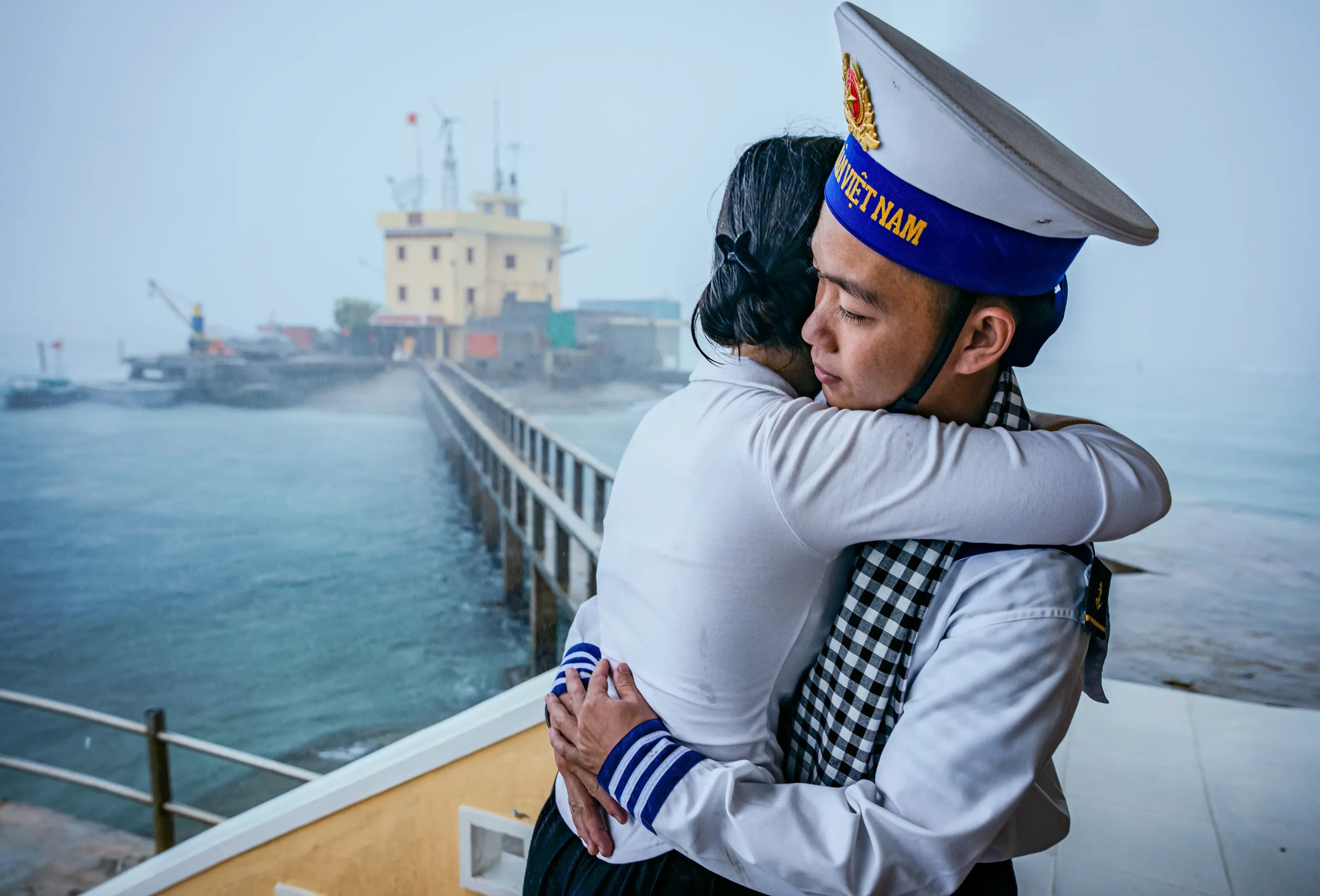 The touching moment when a girl from the West visited her lover, a soldier on Da Tay C island, in the Truong Sa archipelago, Vietnam. In the cold drizzle, they exchanged a lingering and sad farewell hug. The girl gave her lover a checkered scarf, a traditional symbol of the South, as if to convey her deep feelings and attachment to her homeland. This image not only shows the couple's love but also carries the spirit of a marine soldier, with the steadfastness to protect the Fatherland in the middle of the distant and harsh sea.