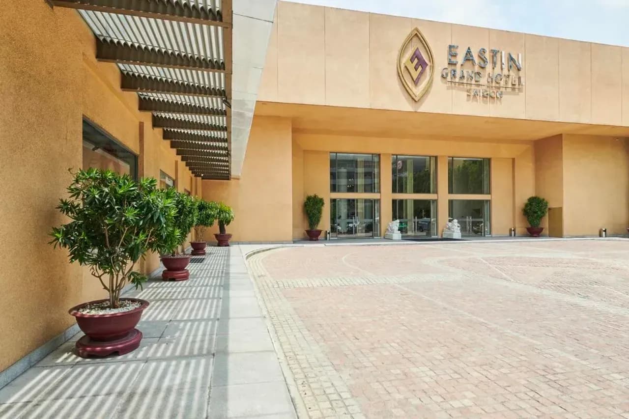 The elegant facade of Eastin Grand Hotel Saigon featuring a modern entrance and decorative greenery.