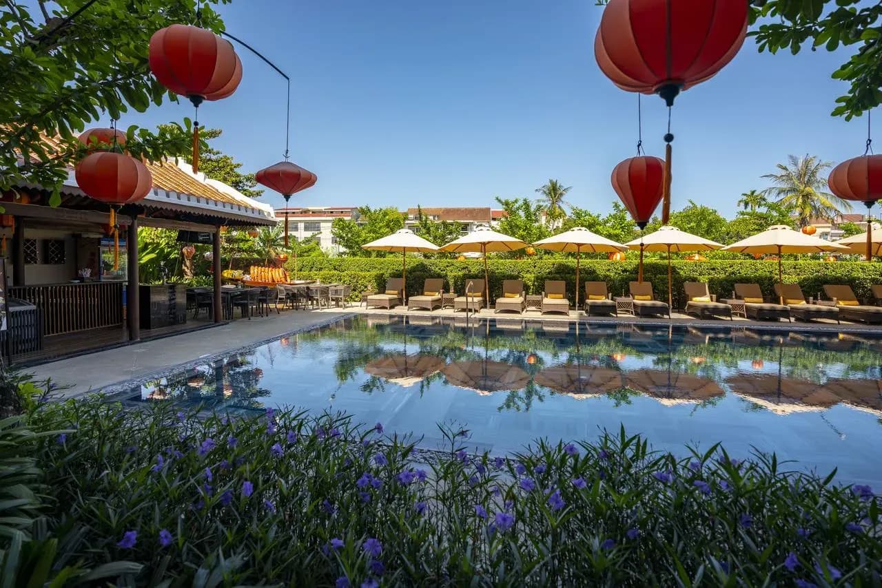 Outdoor pool area at Allegro Hoi An with comfortable seating and vibrant lanterns.