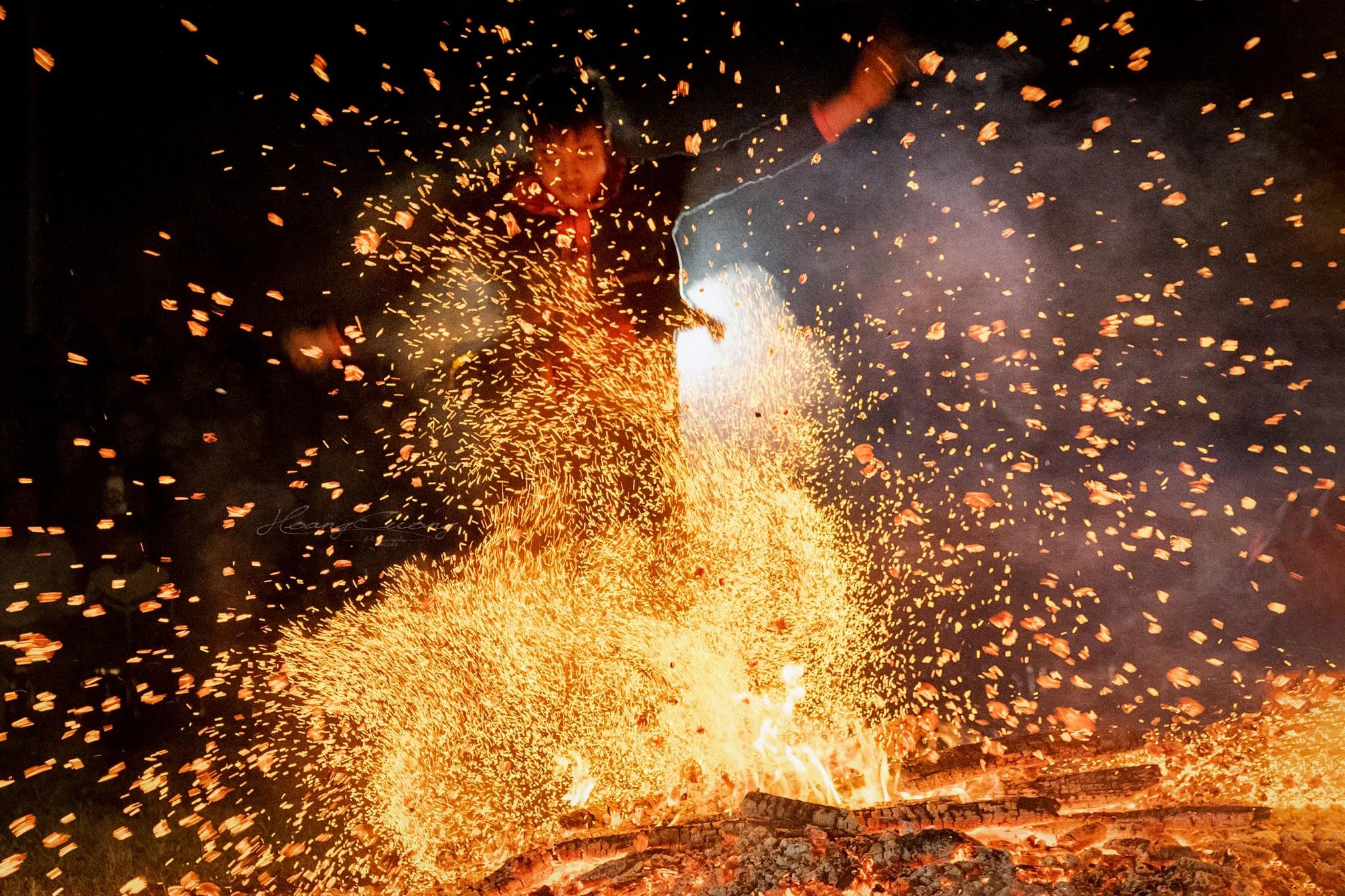 Một người đàn ông người Pà Thẻn đang nhảy trong đống lửa tại lễ hội Nhảy lửa, các hoa lửa bắn tung khắp không gian xung quanh