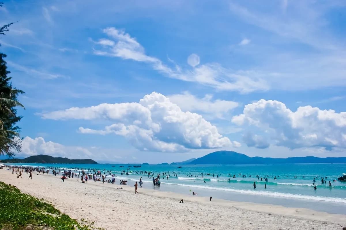 A crowded beach with fine white sand and blue sea.
