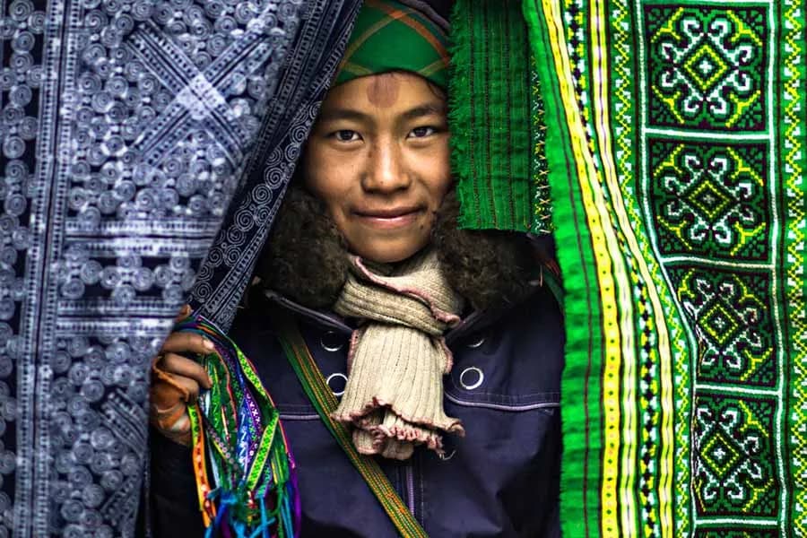 A shy H’mong girl carefully dyeing fabrics, her delicate hands working with traditional tools, surrounded by vibrant colors and patterns