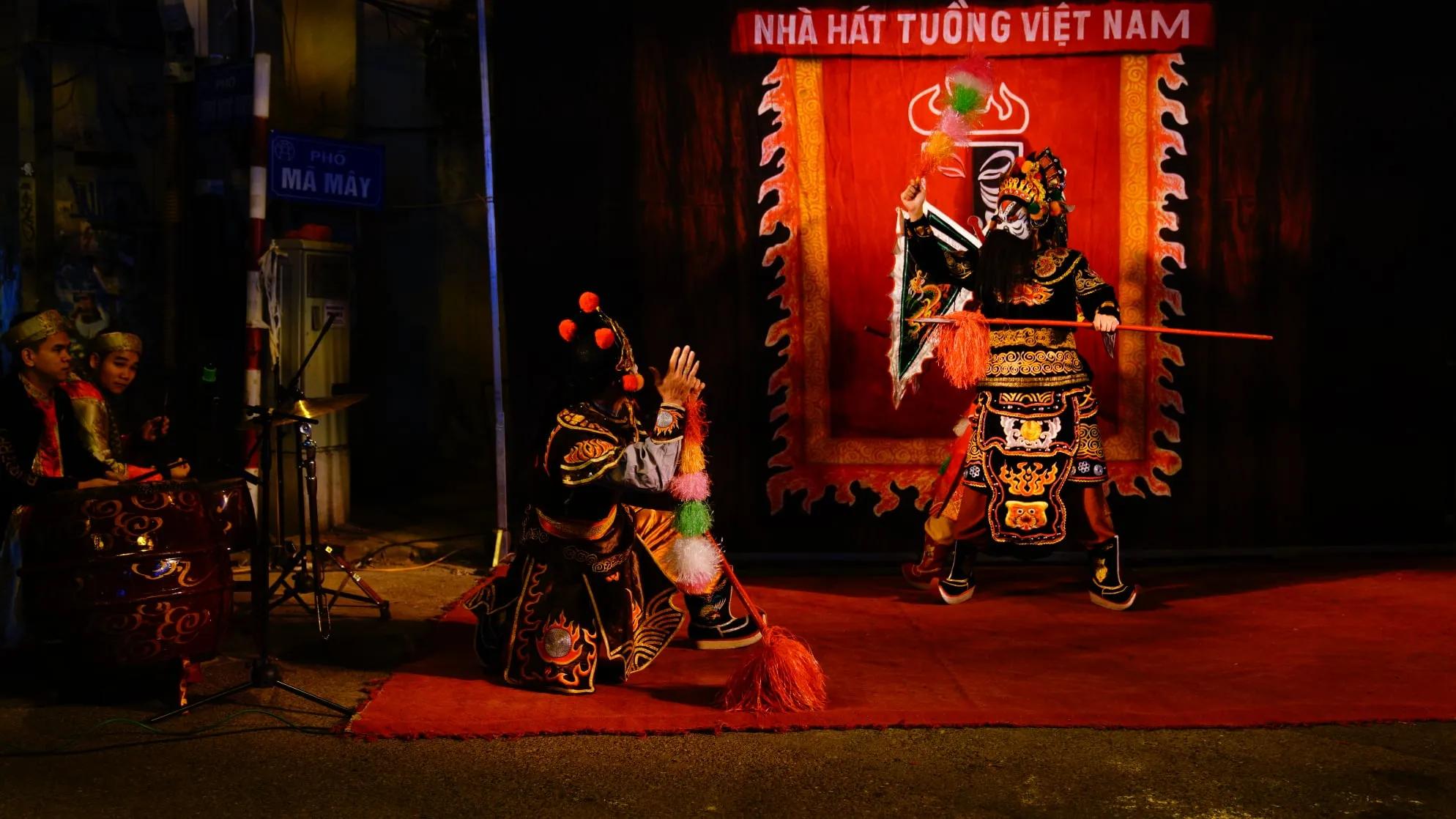 A traditional Tuong performer in vibrant costume captivating the audience on a busy street in Hanoi’s Old Quarter