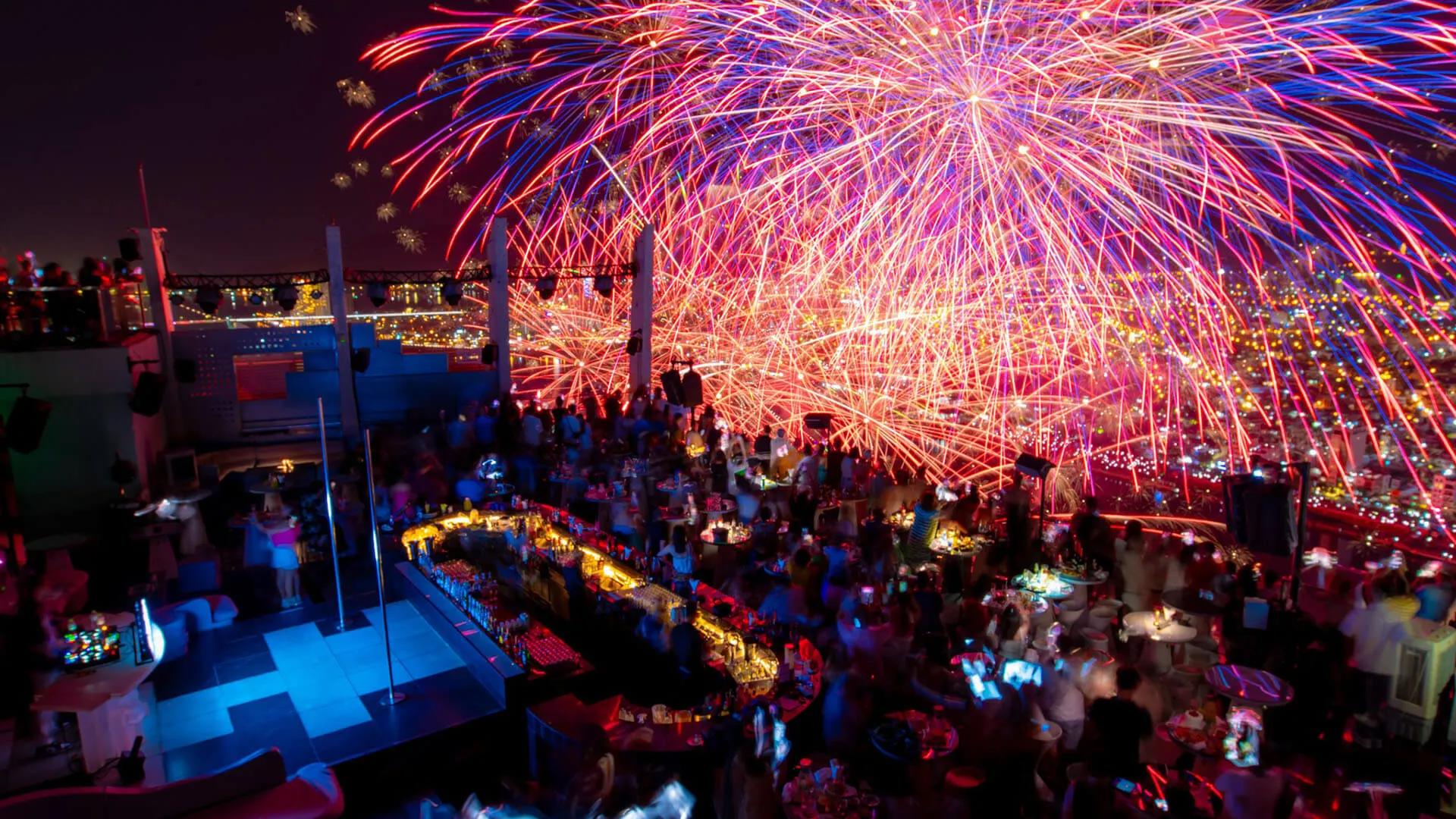 A vibrant view from Sky Bar 36, with fireworks and stunning city lights below and a chic, modern setting for luxury nightlife experiences in the heart of the cit