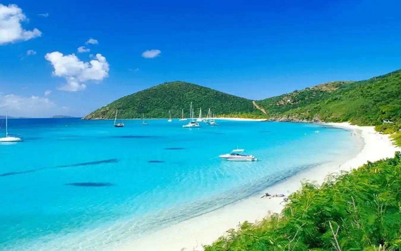 Stunning blue sea with sailboats under a clear blue sky.