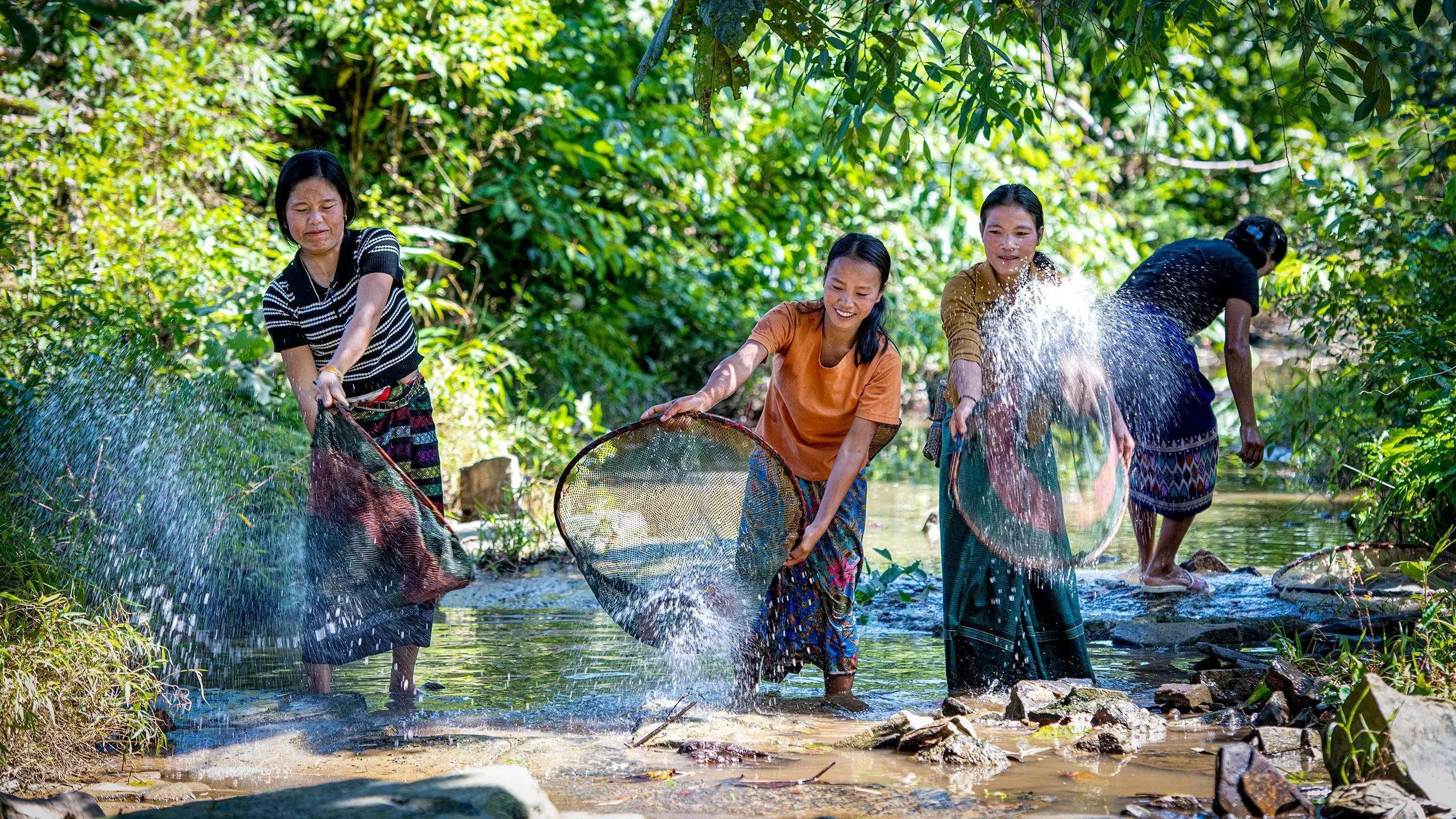 Chut women fishing in the stream, capturing pristine nature.