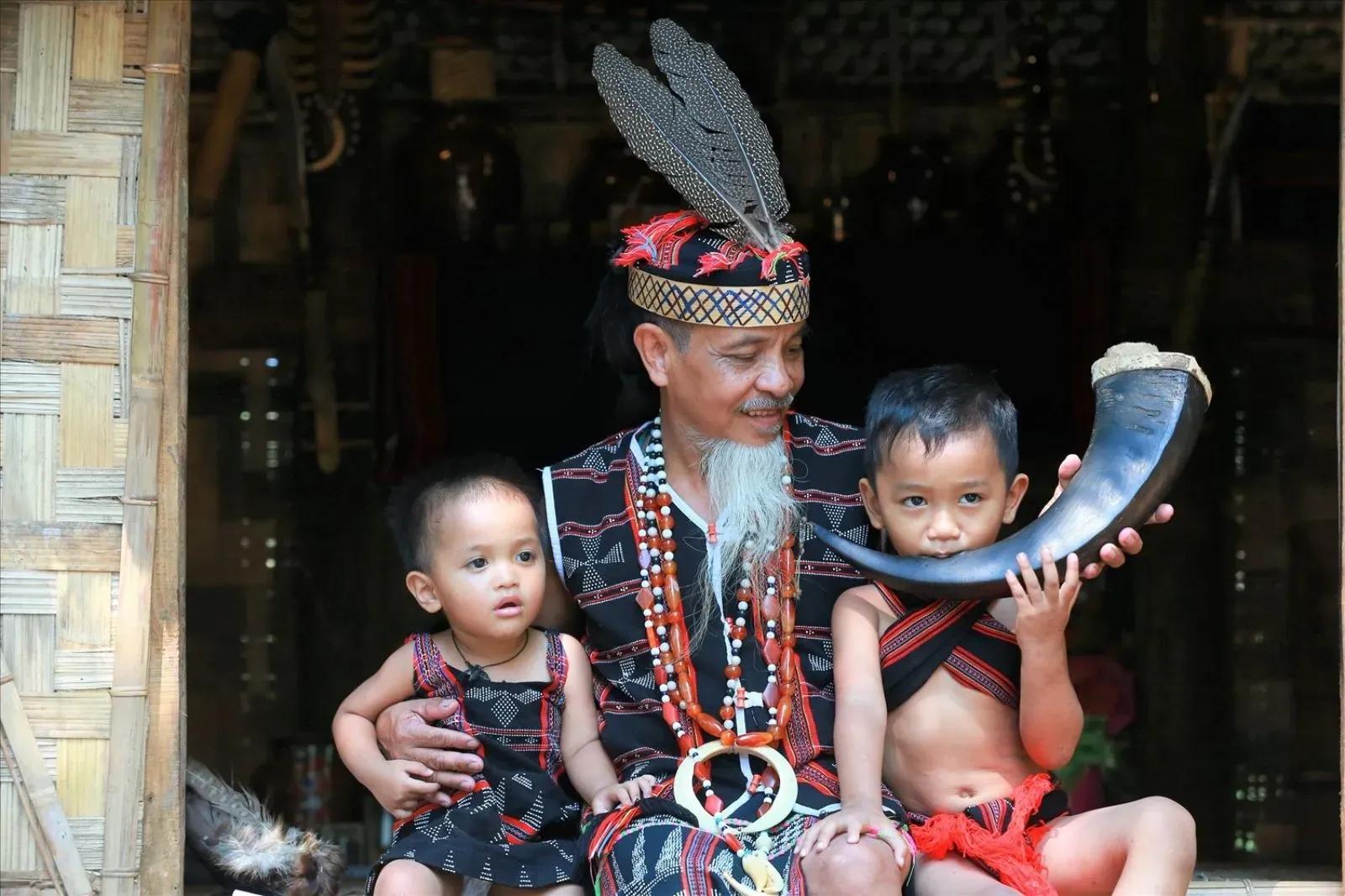 Co Tu man with children in traditional attire.