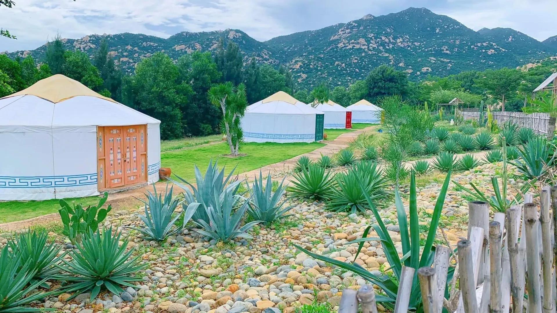Mongolian yurts nestled among lush greenery and majestic mountains.