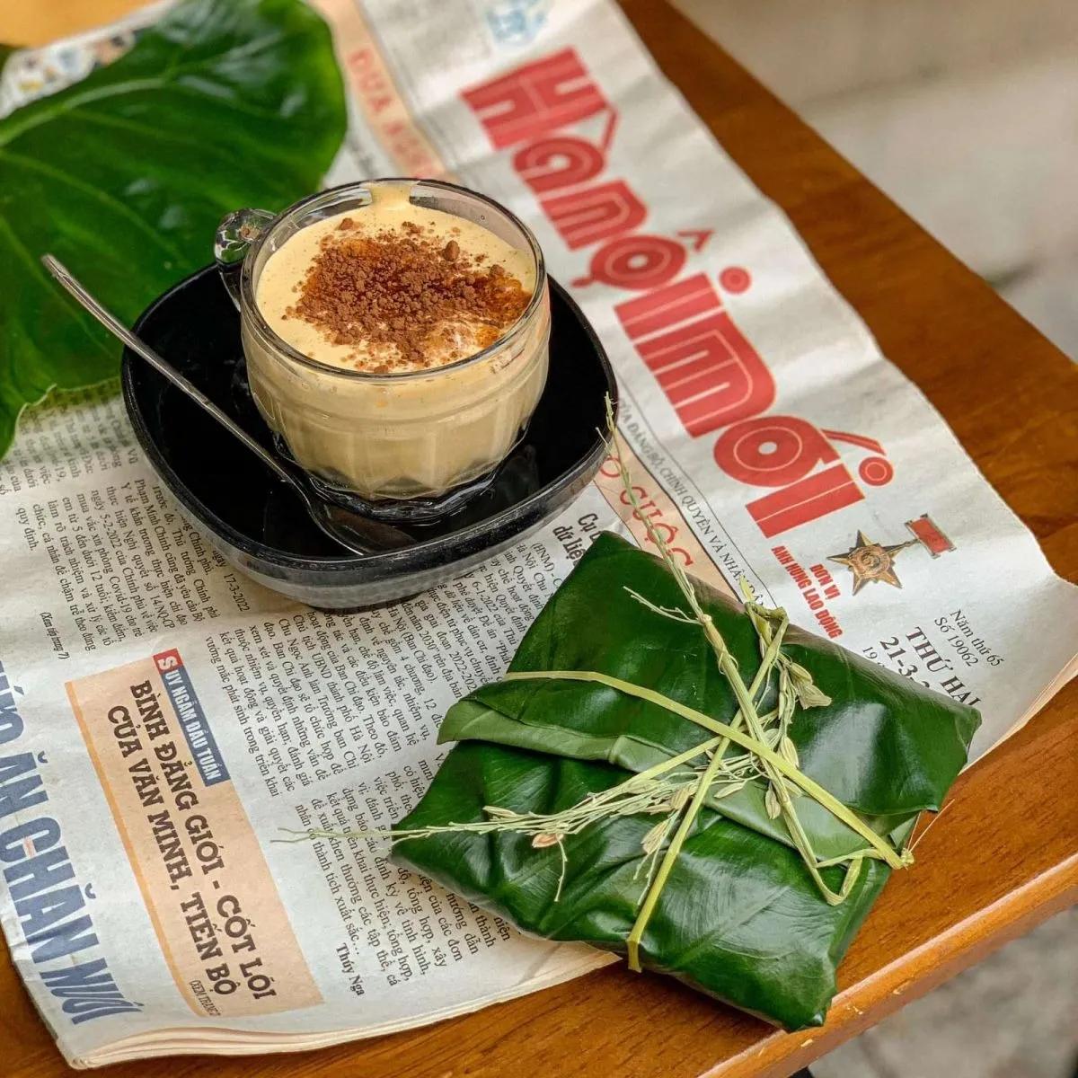 Egg coffee with a traditional Hanoi green rice wrapped in leaf on a newspaper, exuding simplicity.