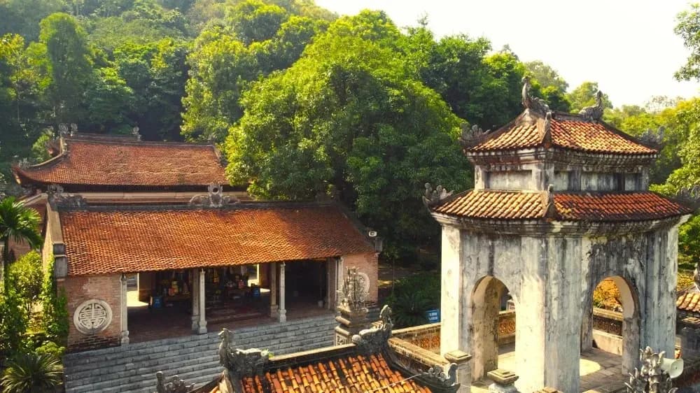 From above, Ba Trieu Temple's mossy red tile roofs stand out against the lush green forest.