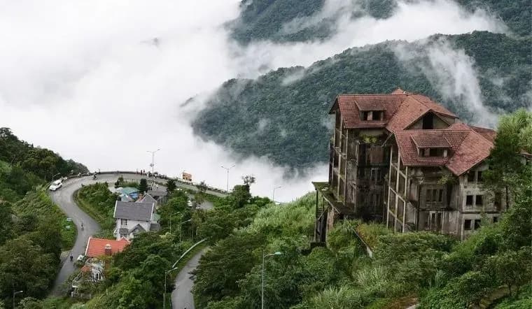 The winding road between lush mountains and white clouds in Tam Dao.