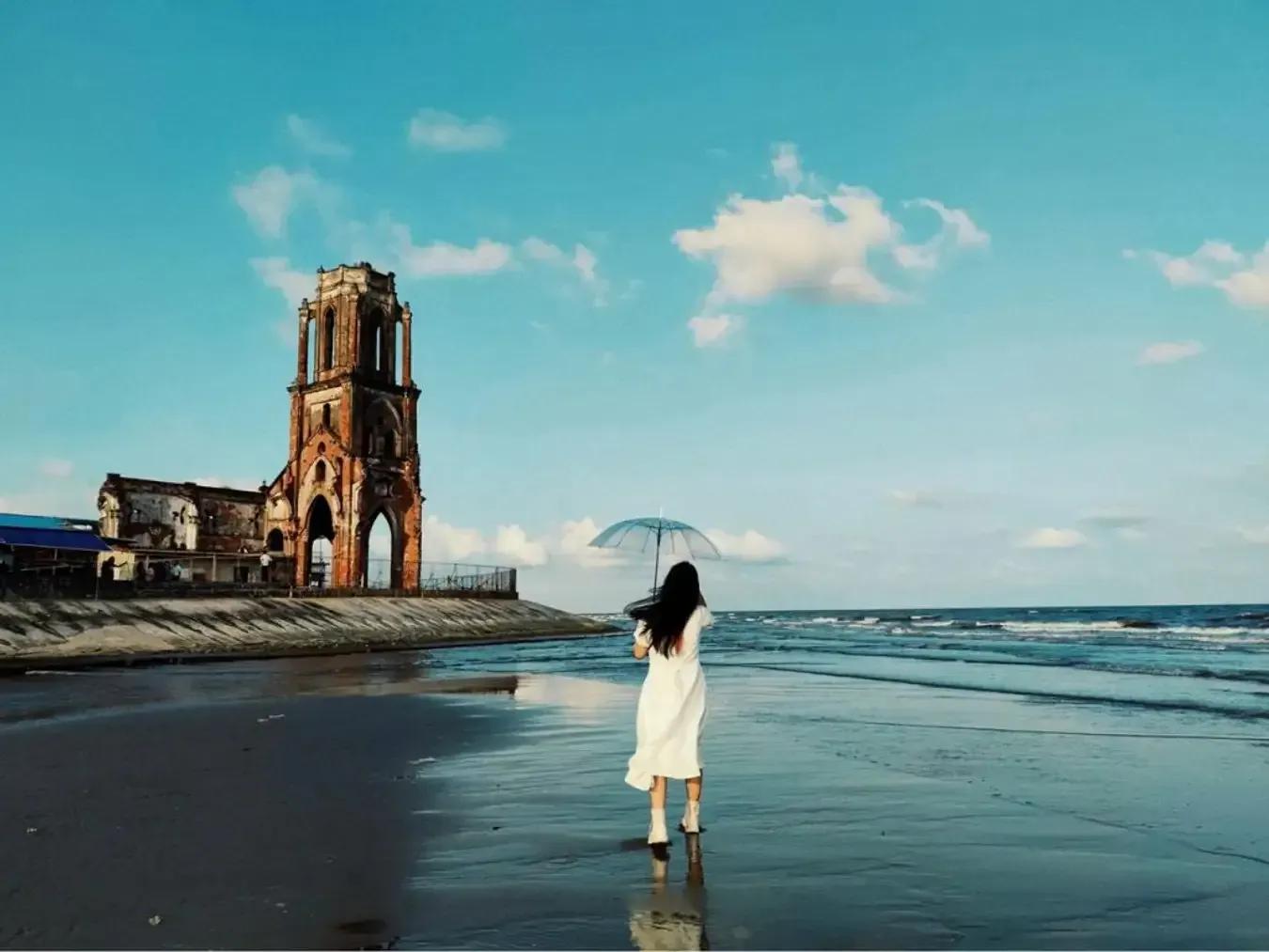 The ancient church and long sandy beach under the blue sky, an inviting stop at Hai Thinh Beach.