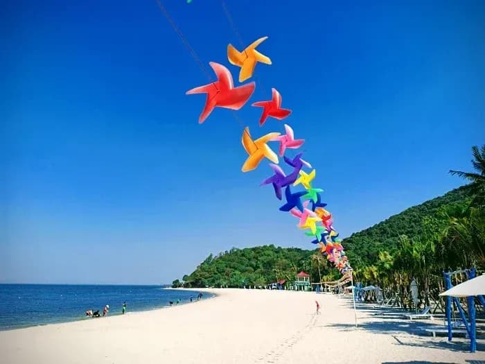 A colorful stream of pinwheels floats over the vibrant Mui Nai beach.