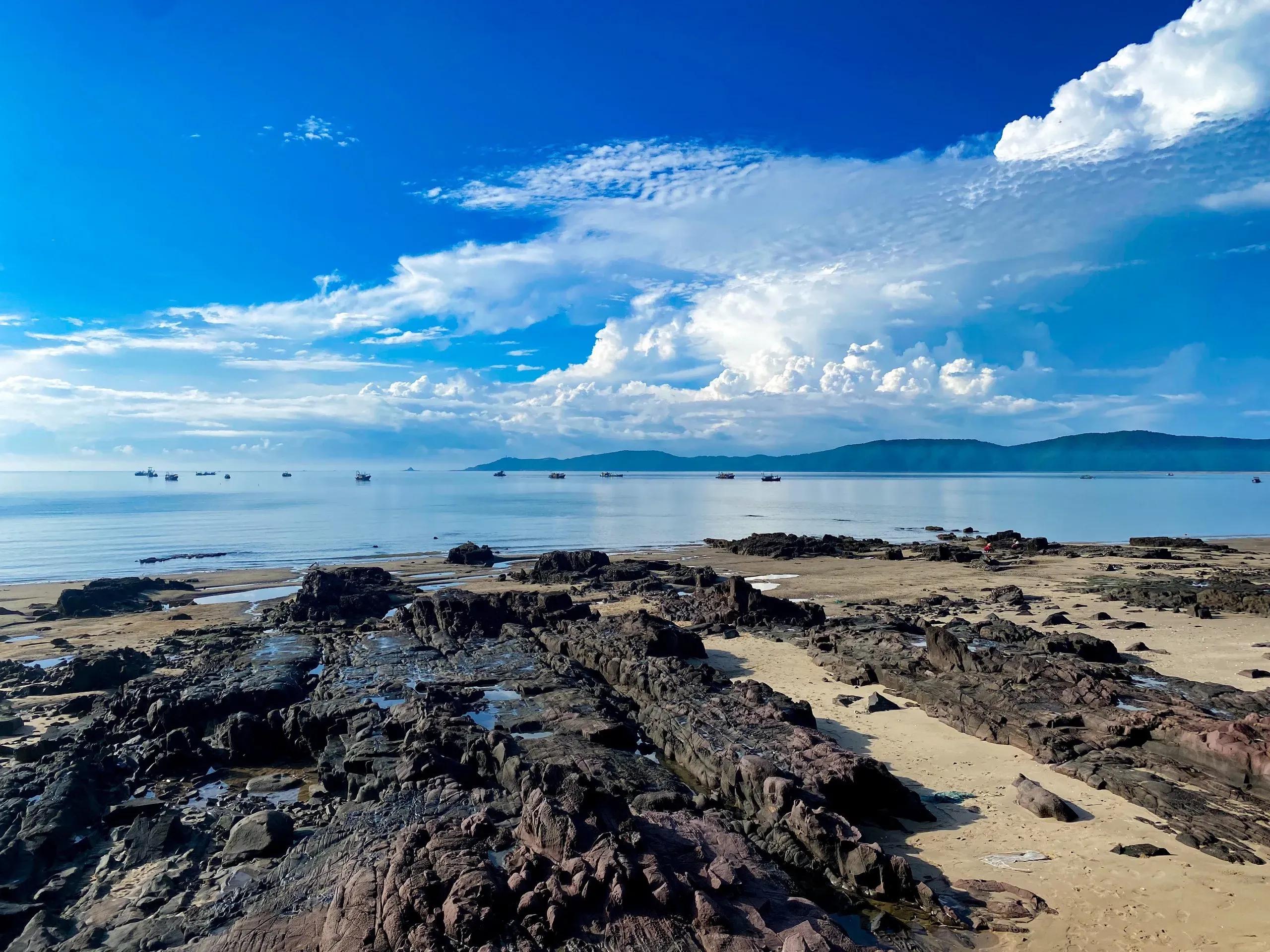 Tra Co Beach offers a stunning view with black stones and a vast blue sky