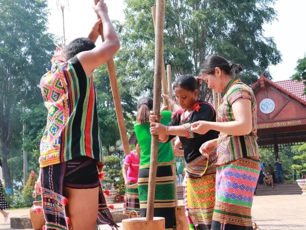 Stieng people pounding rice in a traditional cultural setting.