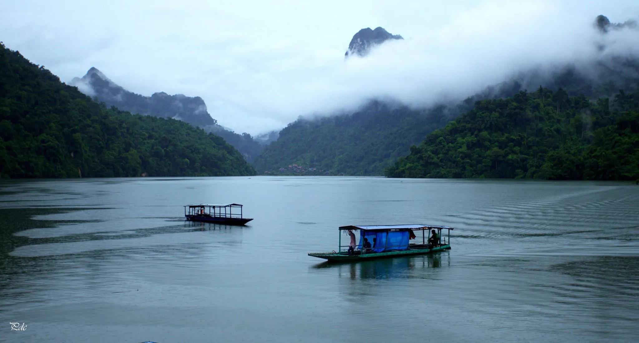 The serene waters of Ba Be Lake surrounded by lush green mountains in Vietnam