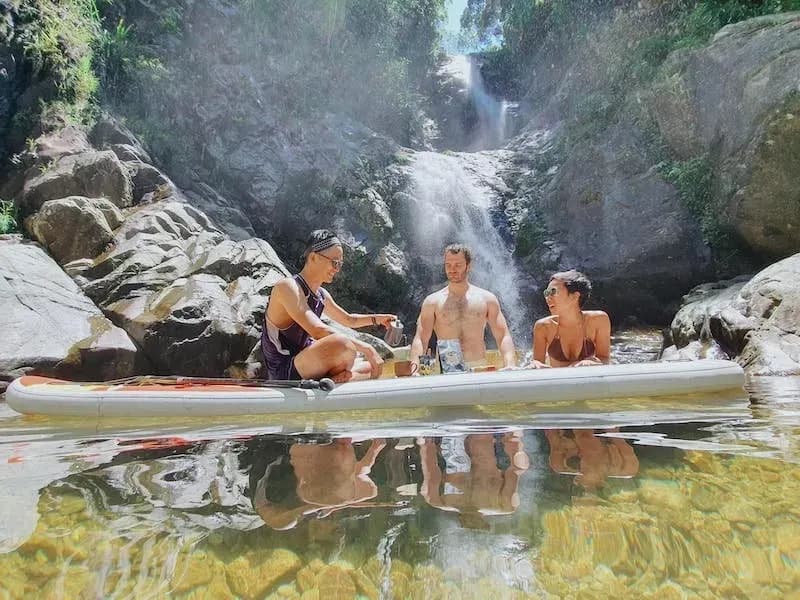 Three people enjoying a meal on a boat under a waterfall.