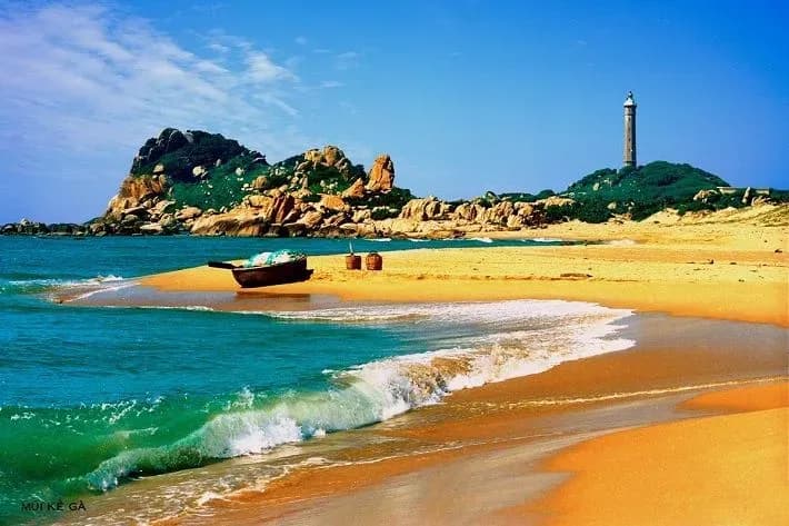 A lighthouse with a beautiful beach where turquoise waters and golden sands blend.