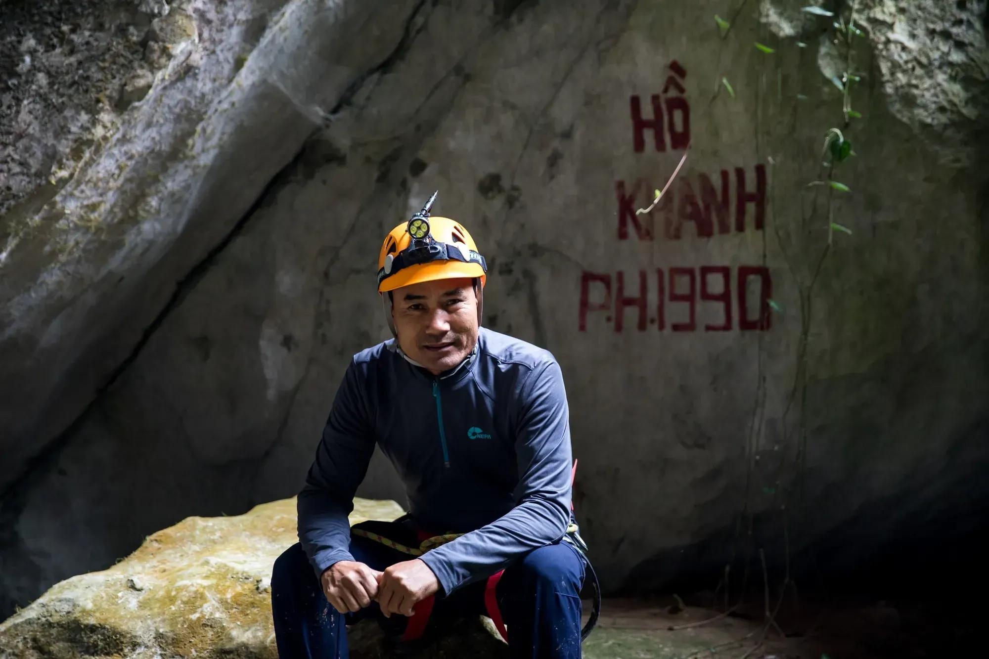 A man sitting inside a cave wearing a safety helmet.