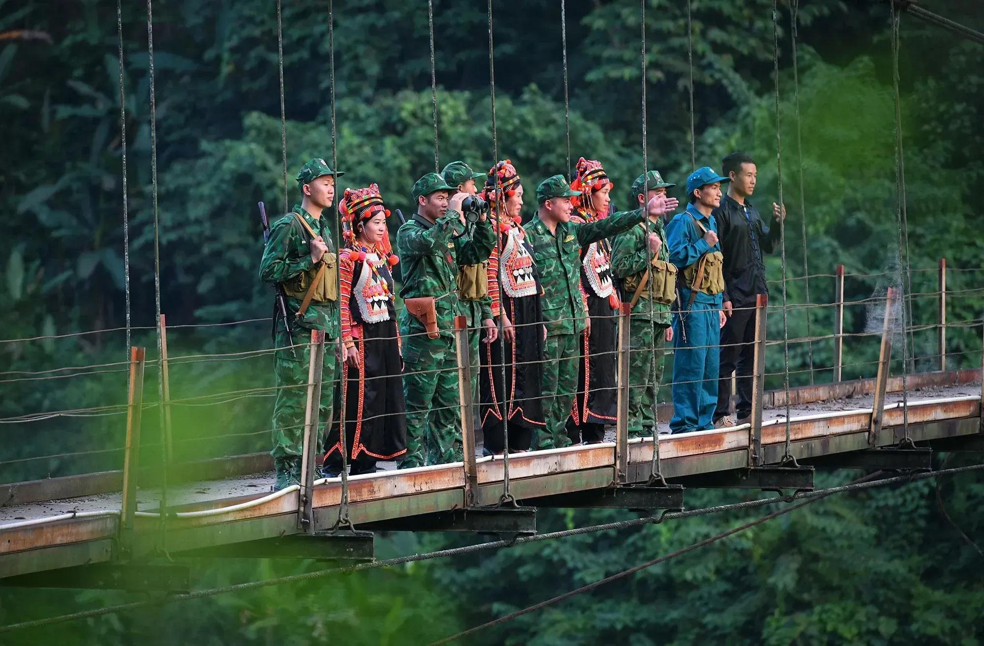 The Ha Nhi people and border soldiers on a suspension bridge amid the lush forest.