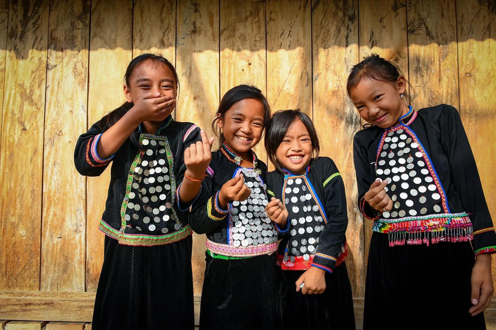 Si La children smiling brightly in vibrant traditional attire, embodying their unique culture.