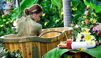 A woman relaxes in a wooden tub, immersing herself in the surrounding nature.
