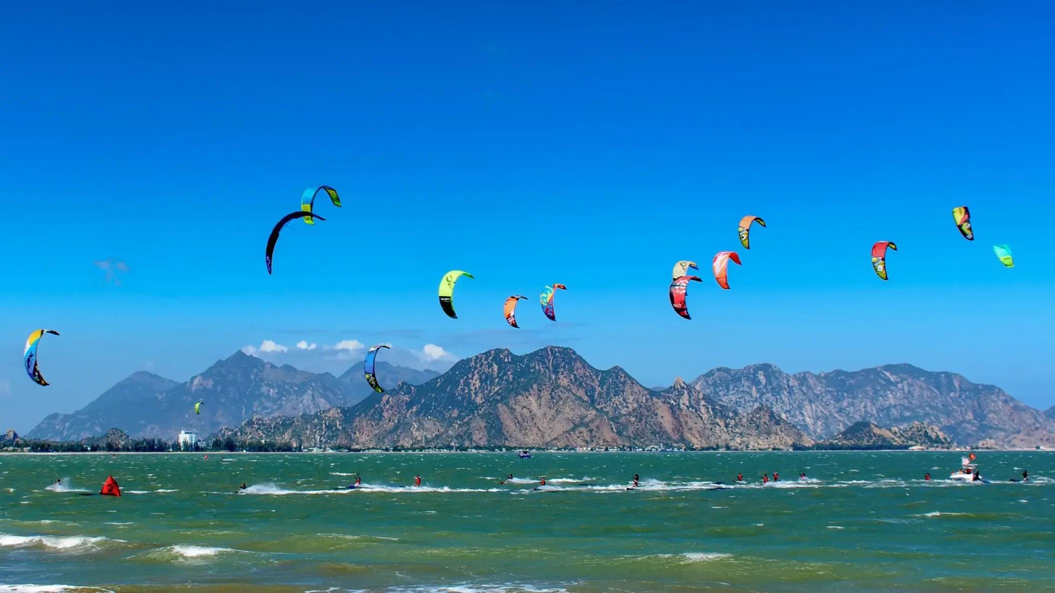 kitesurfers glides across the water in Mui Ne, Vietnam, with the colorful kite soaring high above against a clear sky and the turquoise ocean below