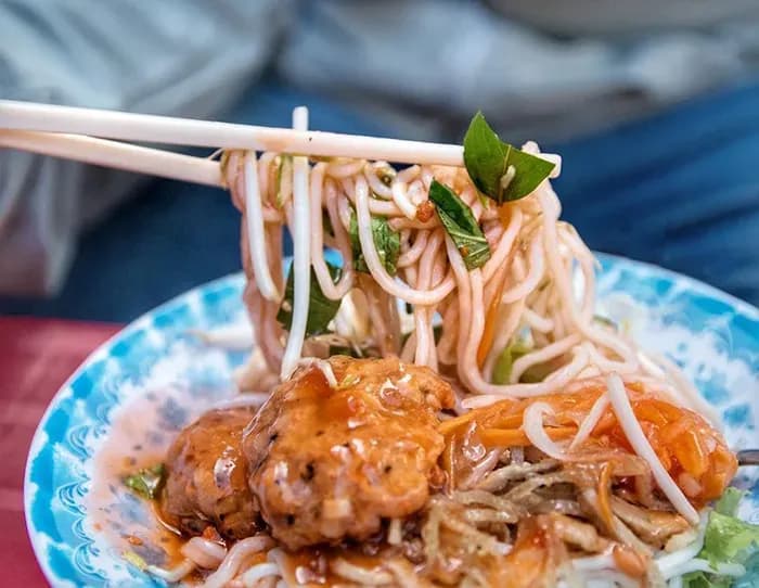 Banh tam bi with rich sauce and fried meatballs.