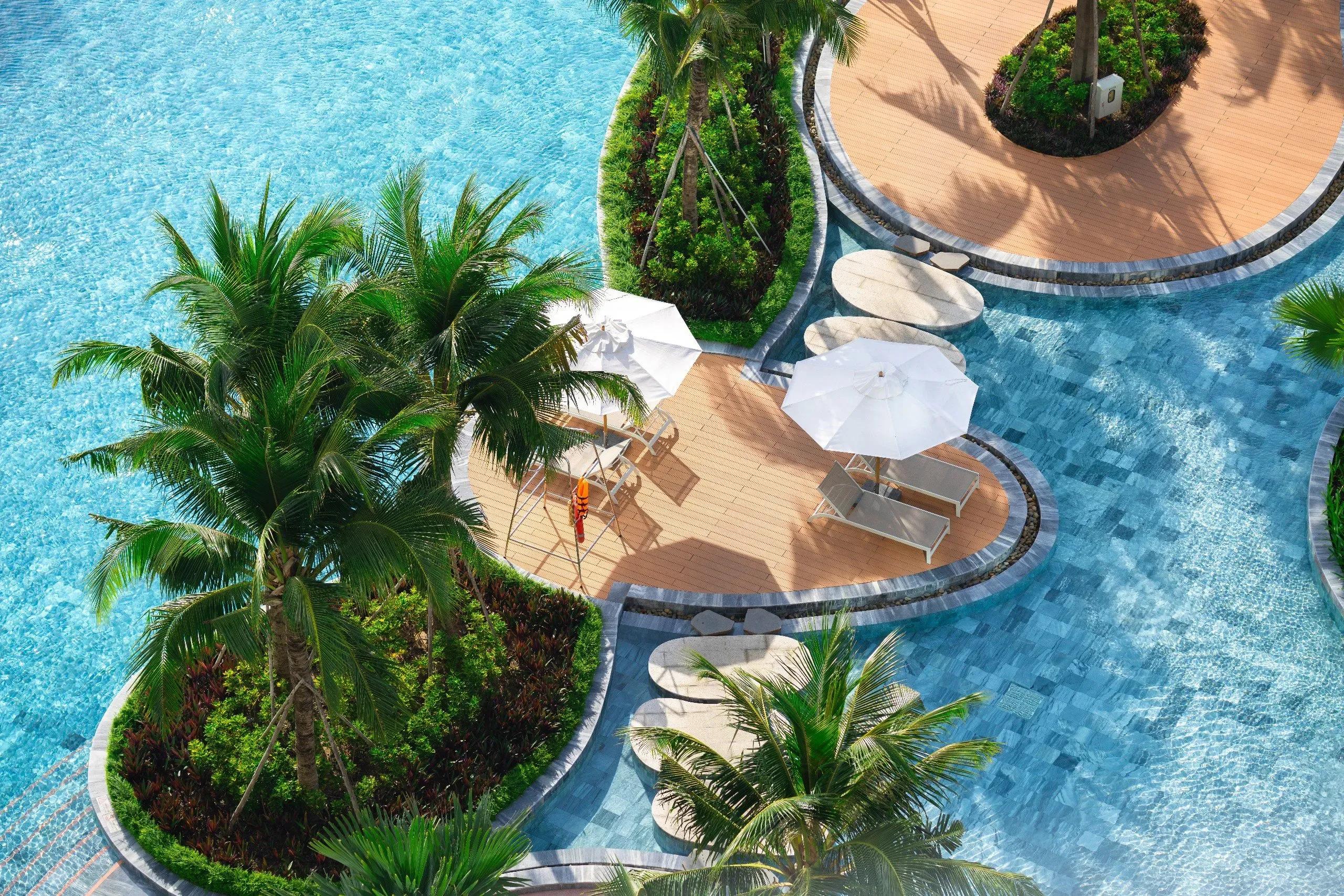 Lush poolside area with white umbrellas at Ho Tram resort.