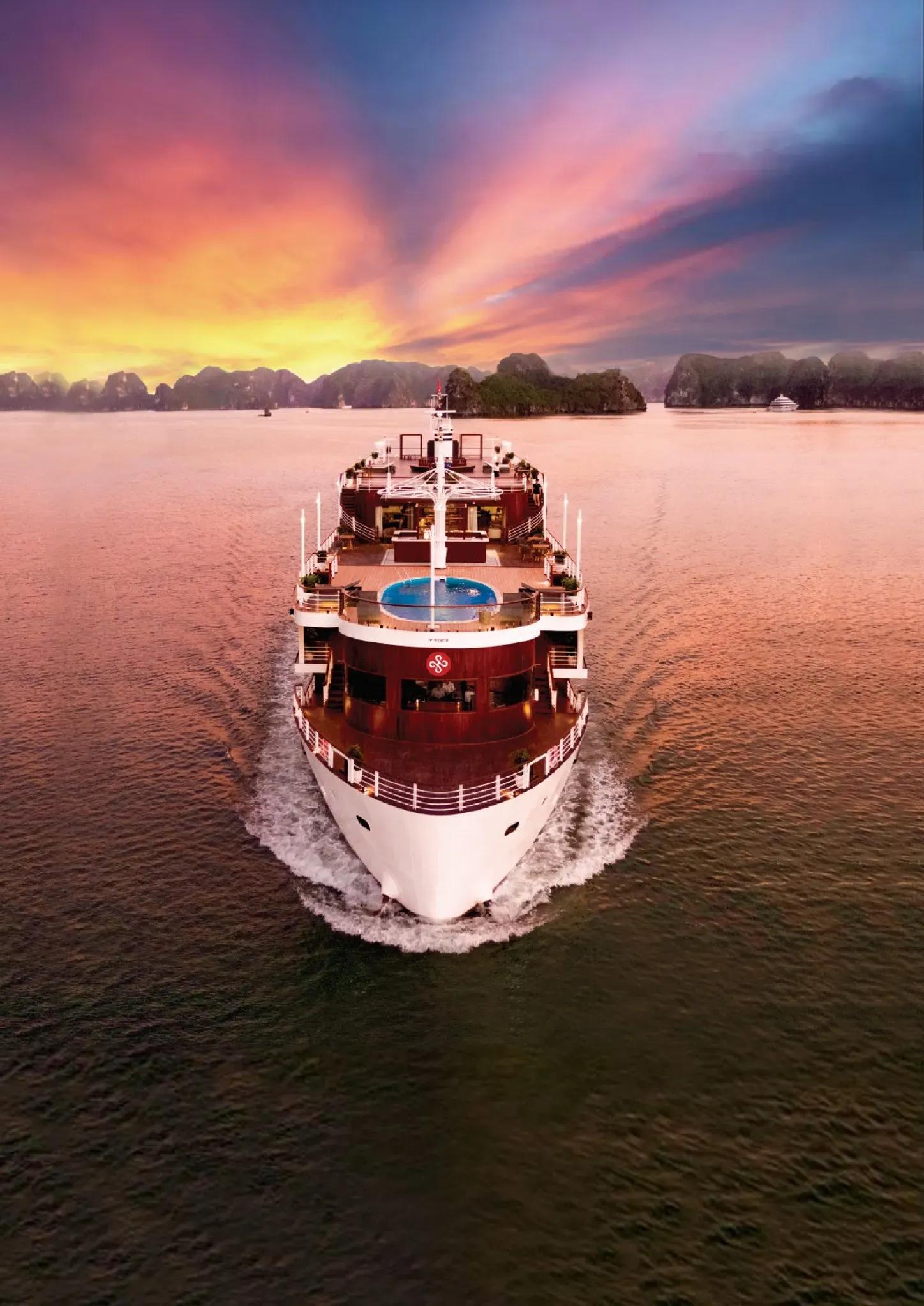 The Heritage Bình Chuẩn cruise illuminated at dawn on Lan Ha Bay.