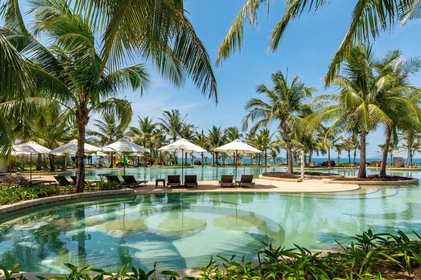 Refreshing pool view surrounded by palm trees.
