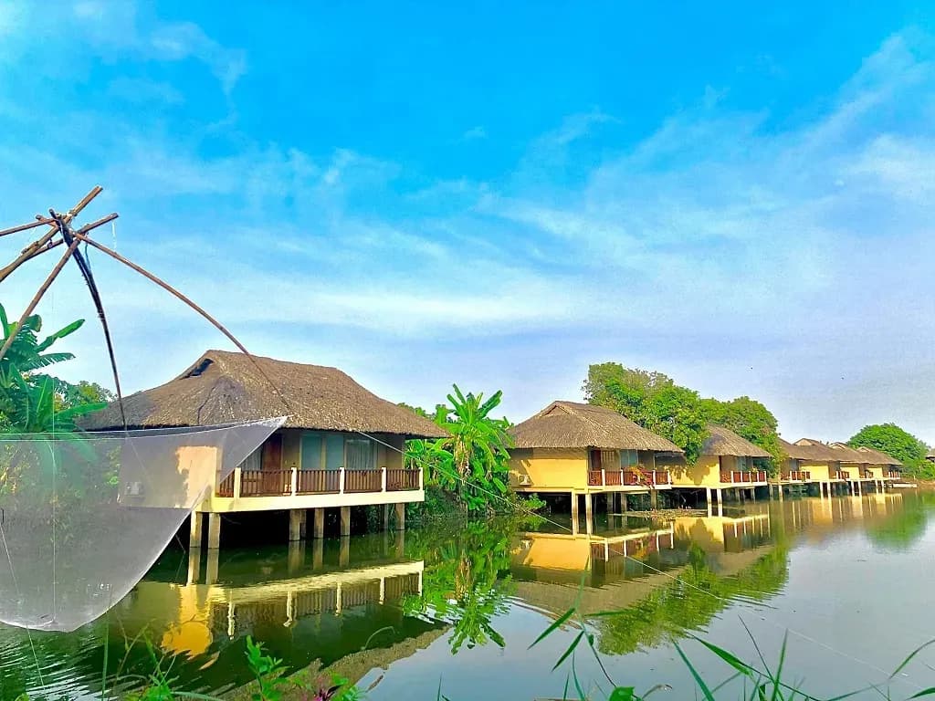Traditional houses on a serene lake, surrounded by lush greenery.
