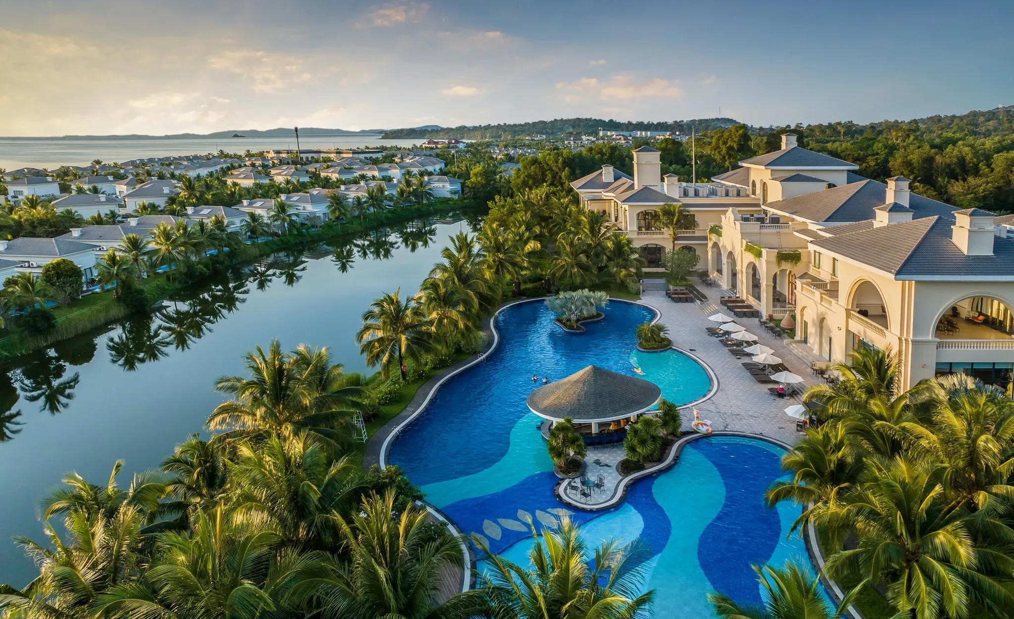 A panoramic view of Vinpearl Wonderworld Phu Quoc with its winding pool and luxurious villas amidst lush greenery.