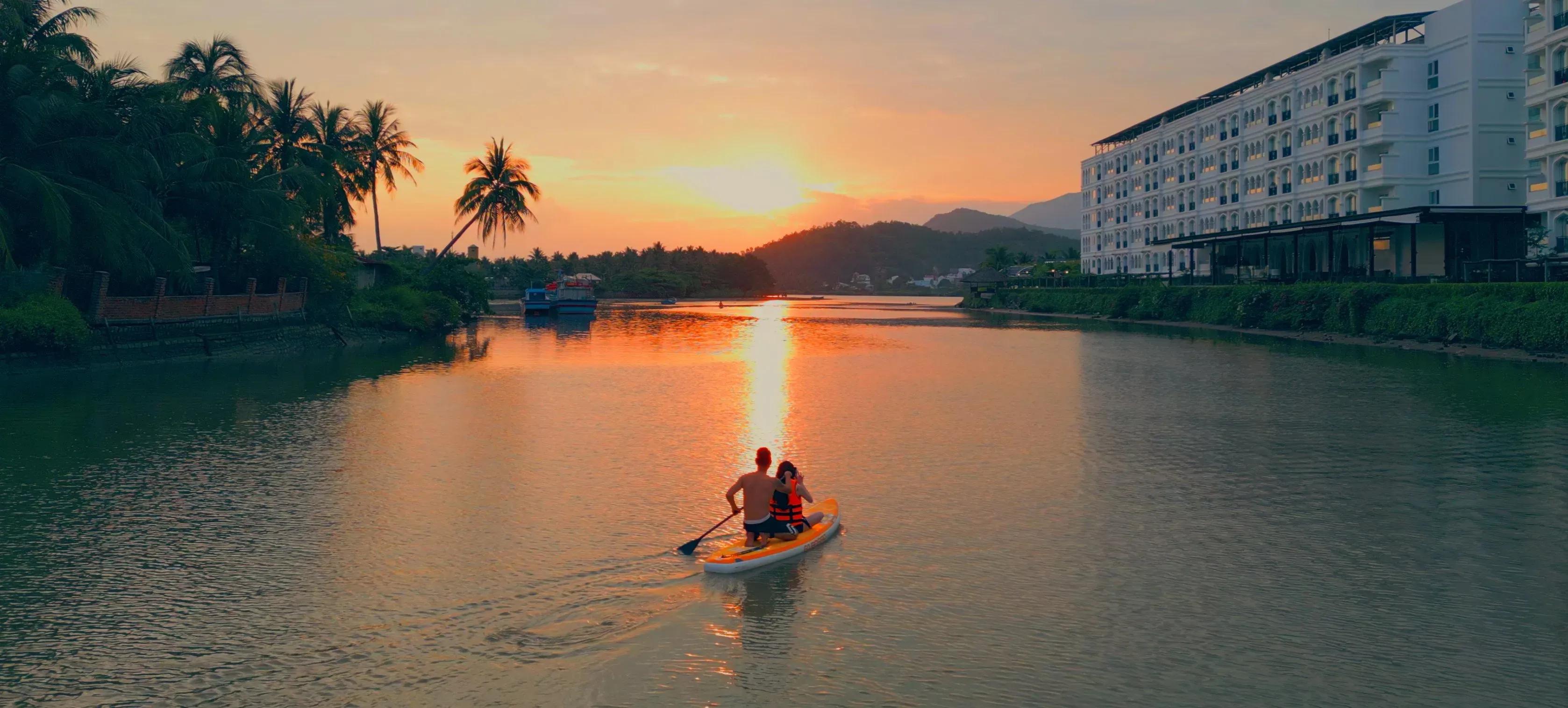 Sunset over the river with two tourists paddling, creating a serene scene at Champa Island.