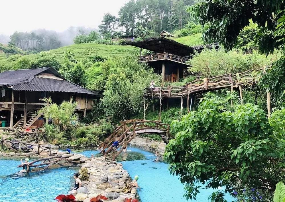Tram Tau hot springs nestled in lush nature, featuring traditional wooden architecture.