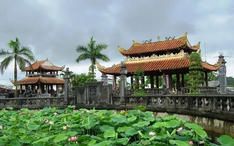 Image of an ancient temple surrounded by a lush green lotus pond.