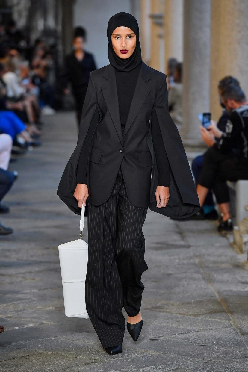 A modest fashion look from Voguebus featuring a stylish model wearing a sophisticated, full-coverage outfit, with elegant layers and modern design, captured in a professional runway setting.