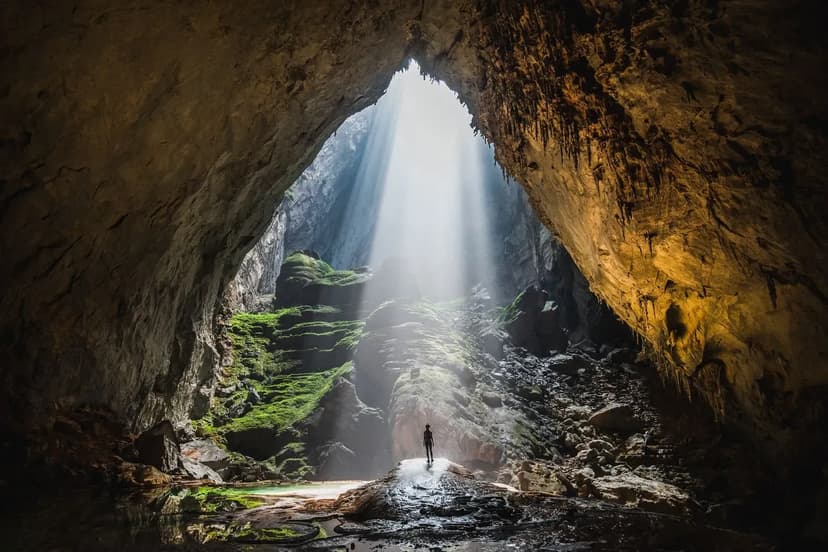 A beam of sunlight shines through the entrance of Son Doong Cave.